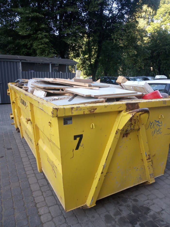 Żółty kontener z deskami, płytami i odpadami z demontażu