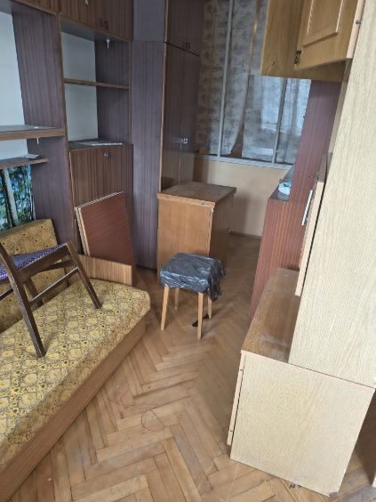 Pokój z meblościanką, wersalką, krzesłem i parkietem w jodełkę